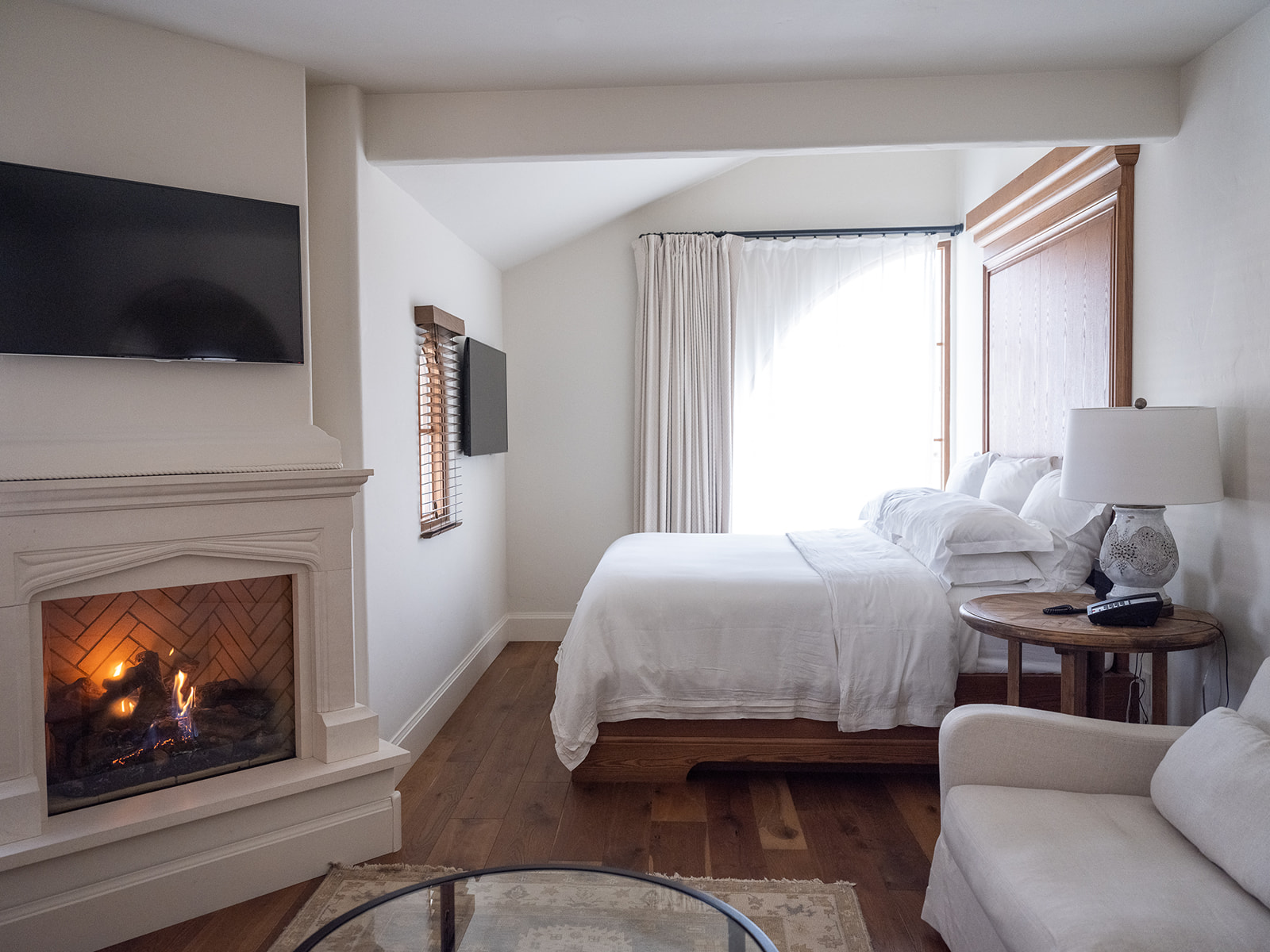 A hotel room with a bed, fireplace, TV, and sofa.