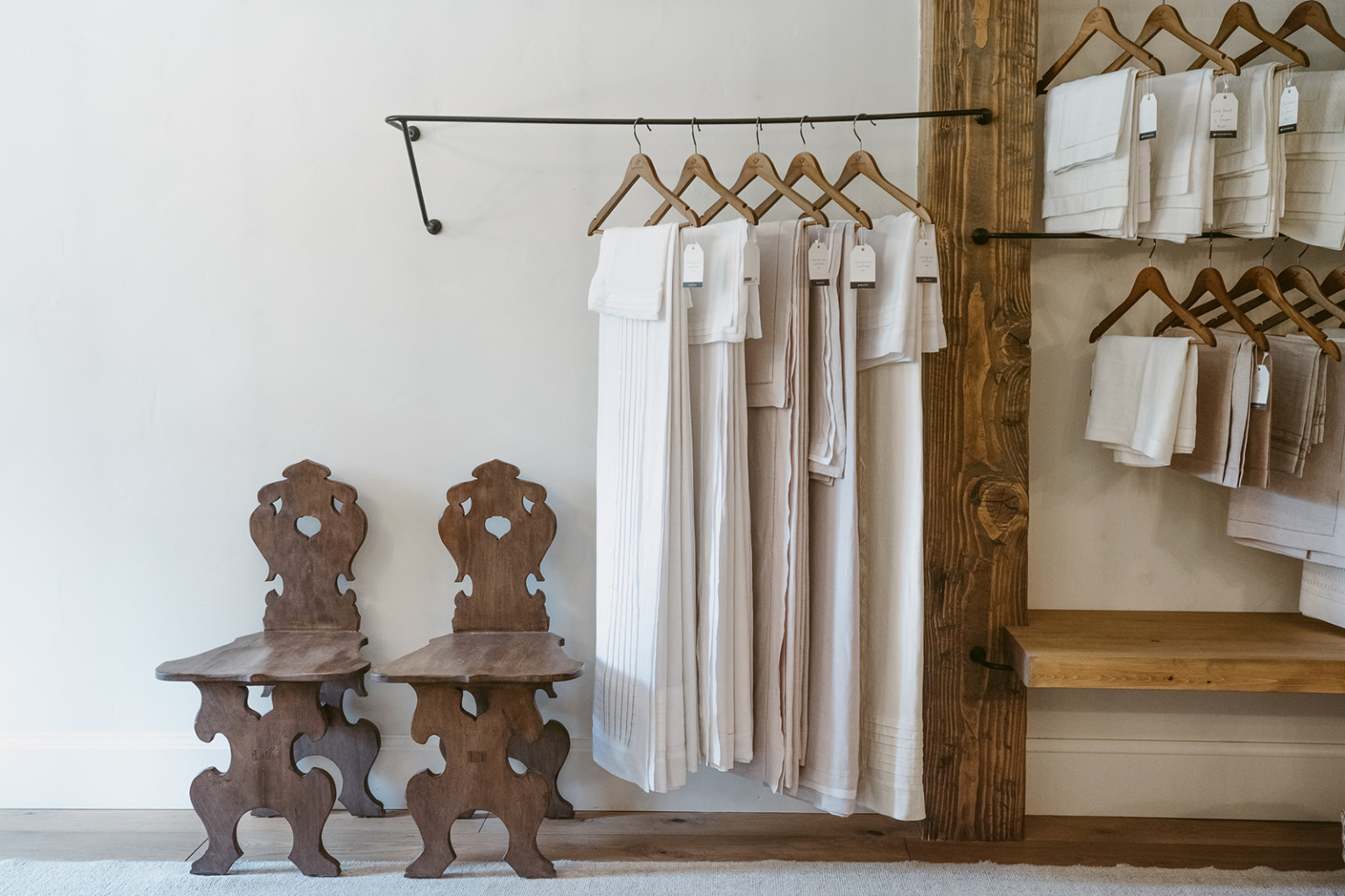 A selection of white robes and towels hanging on wooden hangers in a spa.