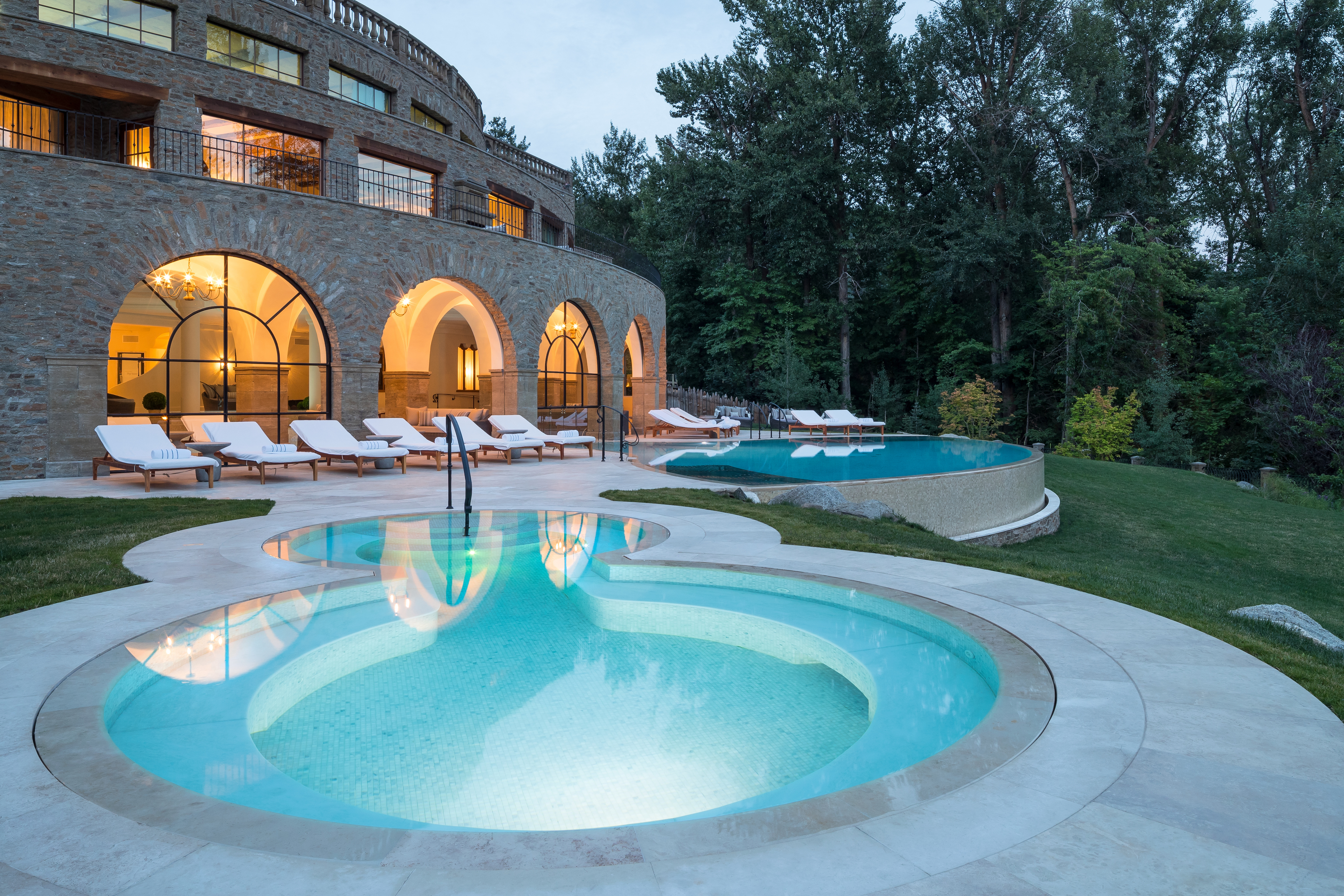A curved pool with lounge chairs and a building in the background