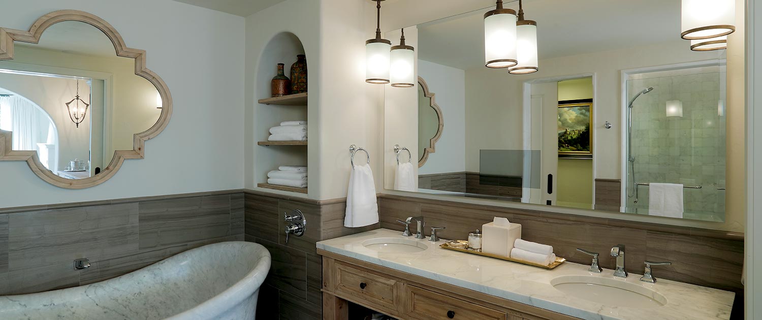 A bathroom vanity with a large mirror, a sink, and a bathtub, with towels and toiletries on the shelves.